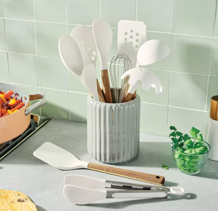 White utensils in a ceramic container on a kitchen counter