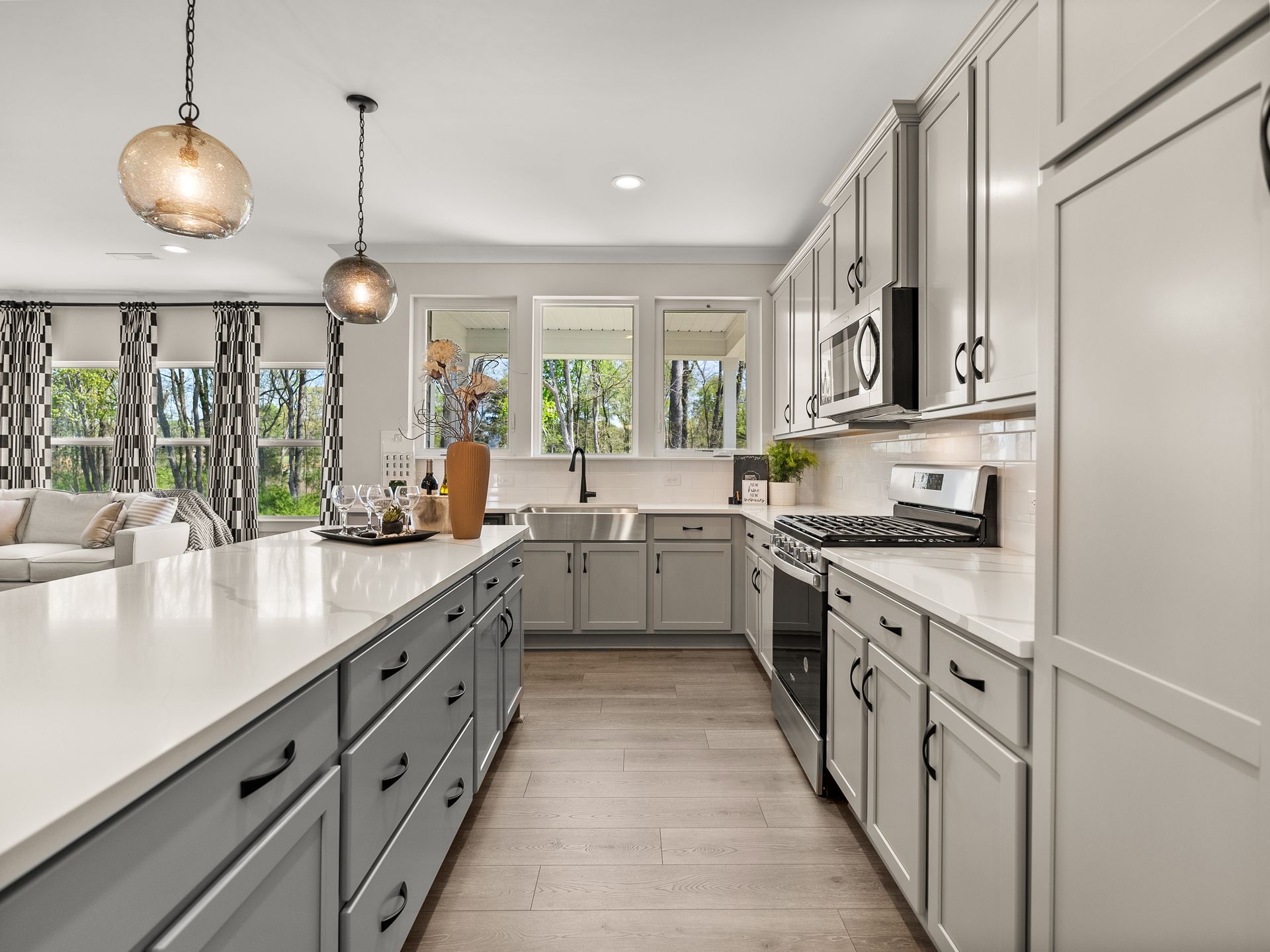 A kitchen in a model home with white cabinets and stainless steel appliances.