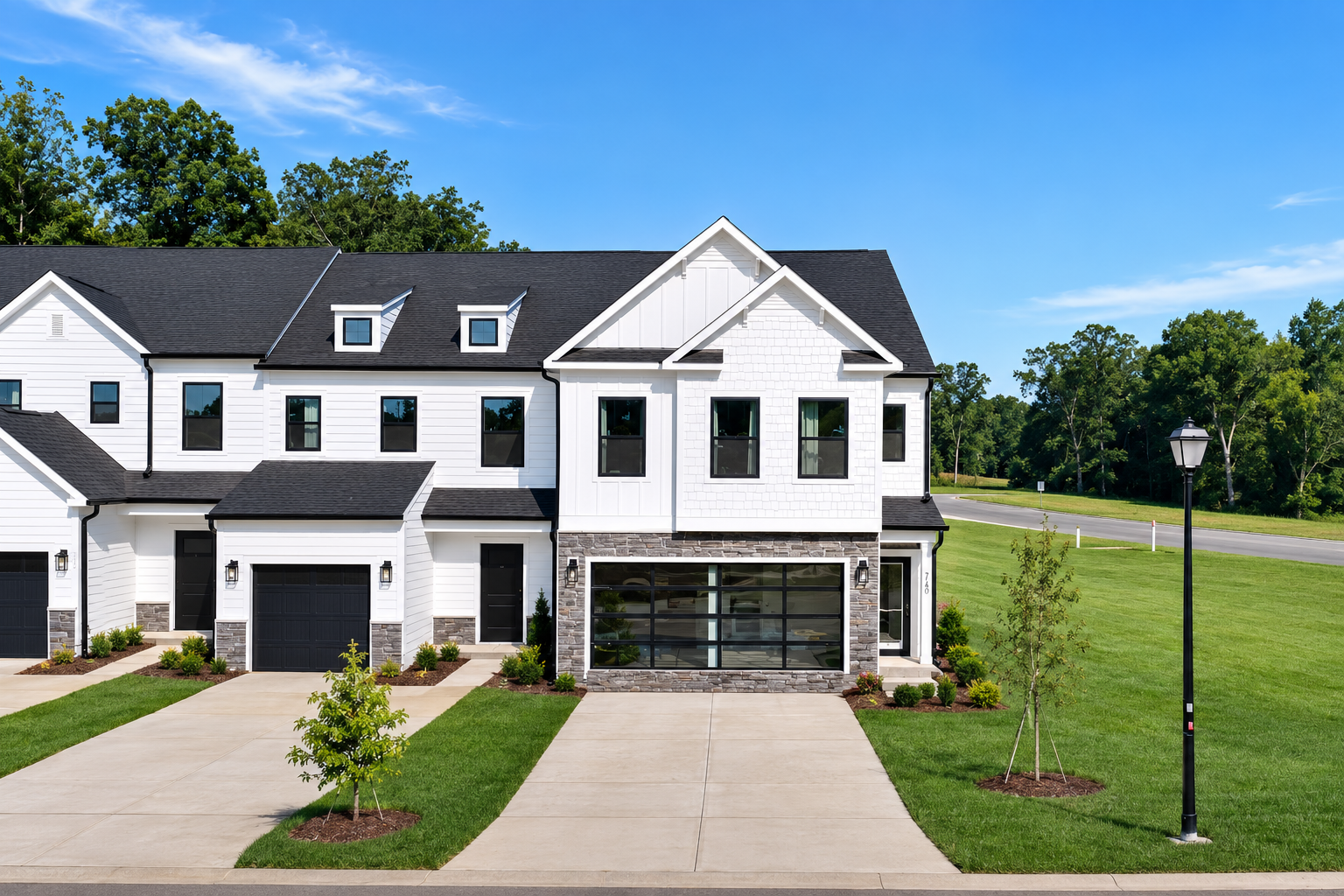 Two-story house with blue siding, stone facade, and a green lawn on a sunny day.