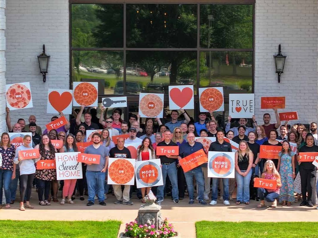 Group of people holding signs with orange hearts & the word