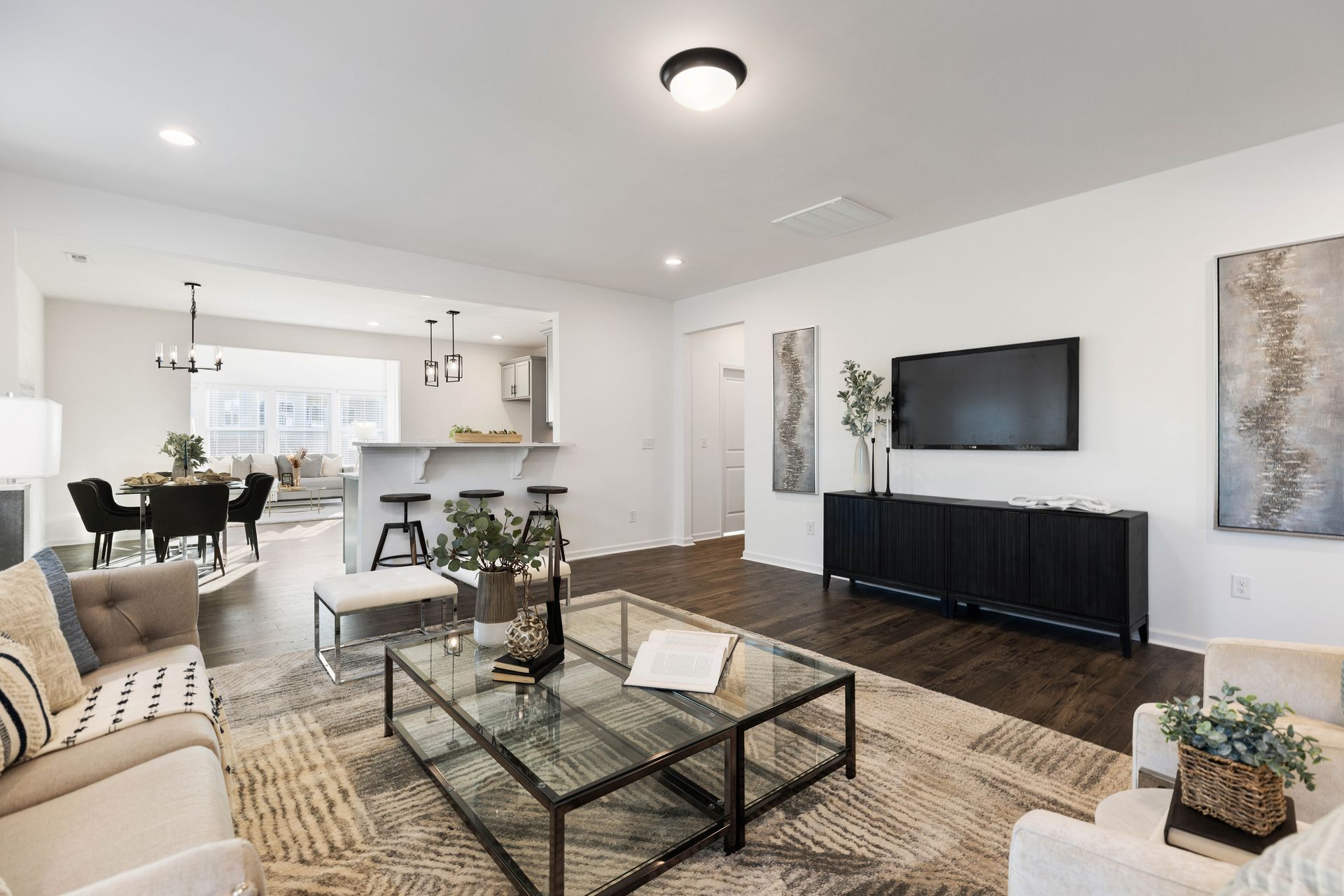 Modern open-concept living room with sectional sofa, glass coffee table, TV, and dining area