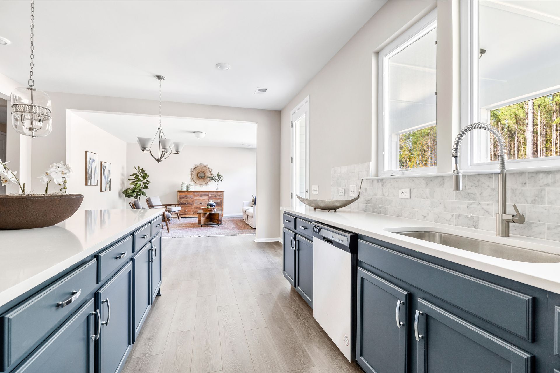 Bright modern kitchen with blue cabinets, white countertops, and large windows overlooking a dining area