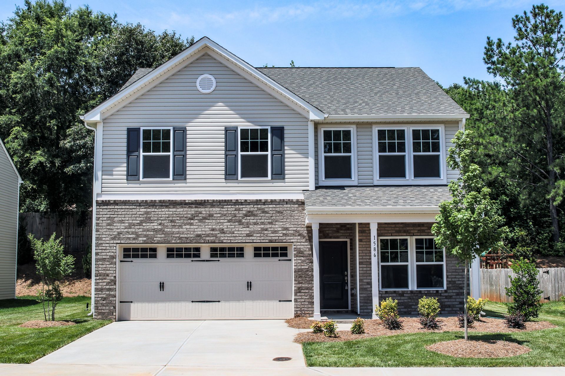 Two-story house with stone facade and light blue siding, blue shutters, and two-car garage.