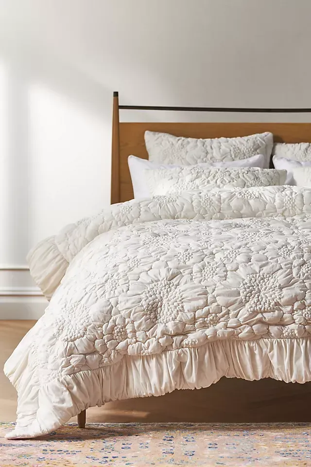 A bed with a white comforter and pillows on it.