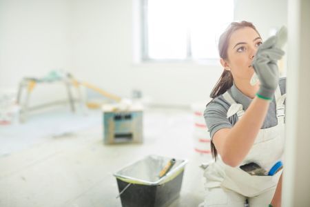 A woman is painting a wall in a room.