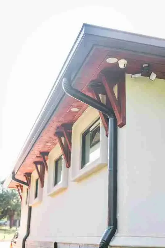 A white house with a black gutter on the side of it.
