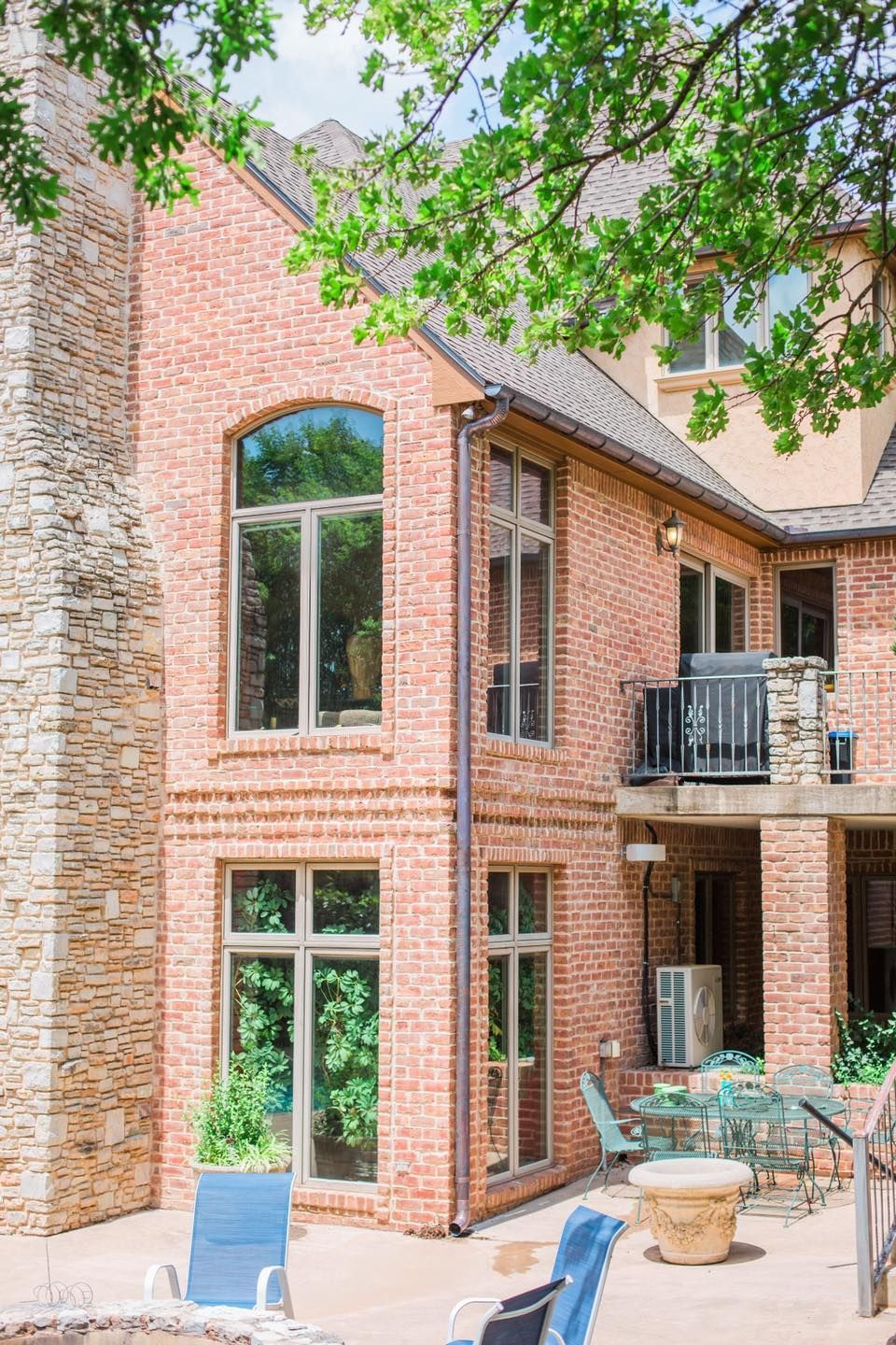 A large brick house with a patio and a fire pit in front of it.