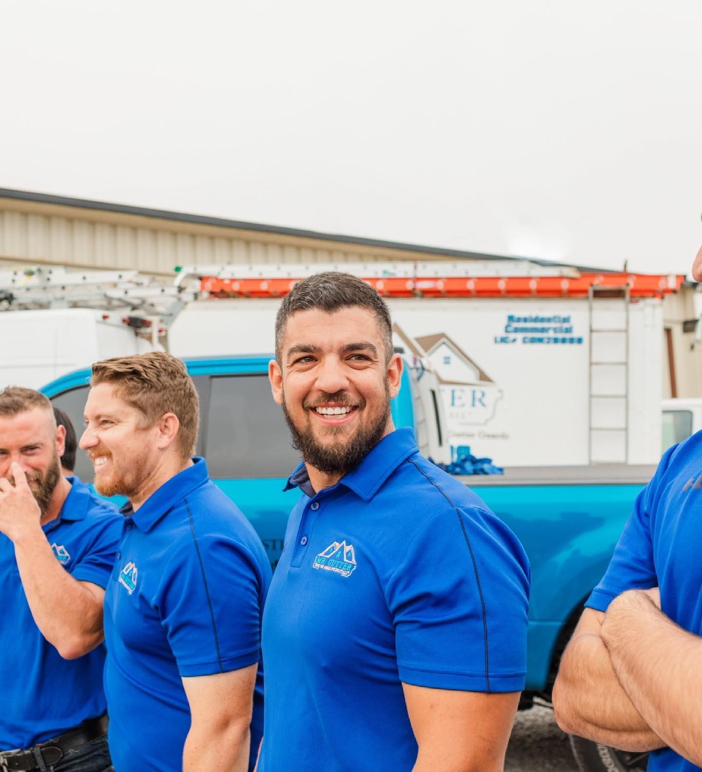 A group of men wearing blue shirts are standing in front of a truck.