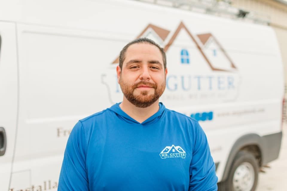 A man in a blue shirt is standing in front of a white van.