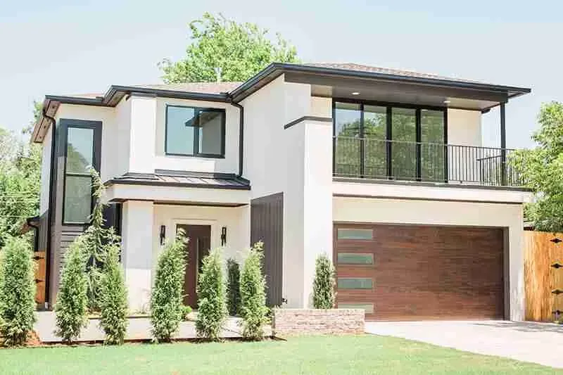A modern white house with a large garage and a balcony.