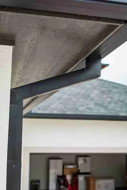A close up of a gutter on the side of a house.
