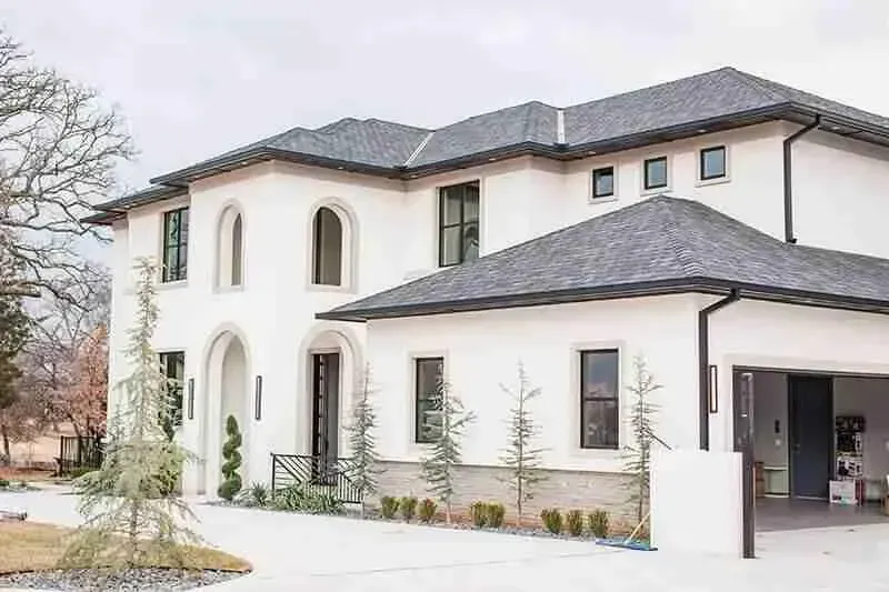 A large white house with a black roof and a garage.
