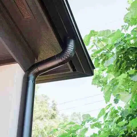 A close up of a black gutter on the side of a house.