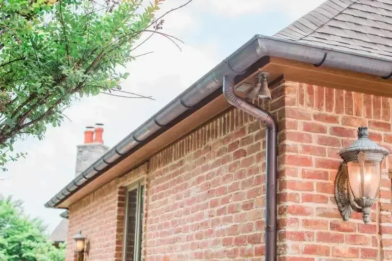 A brick house with a gutter on the side of it.