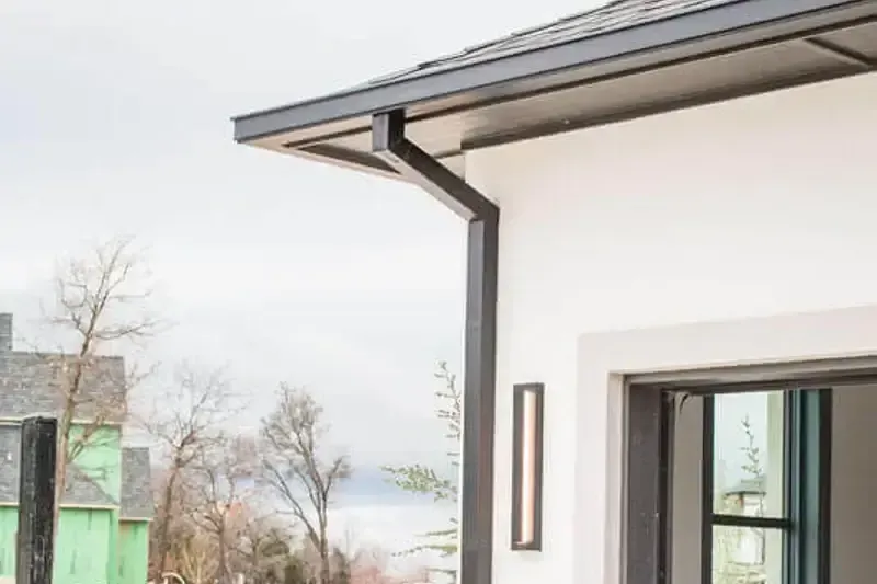 A white house with a black gutter and a sliding glass door.