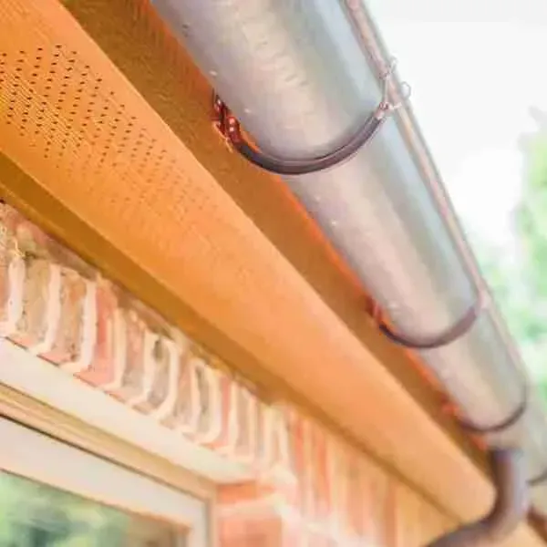 A close up of a gutter on the side of a brick building.