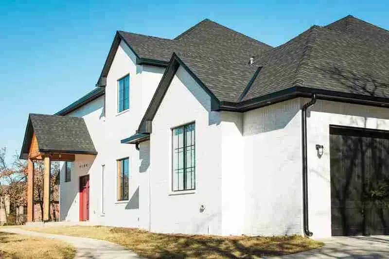 A white house with a black garage door and a black roof.