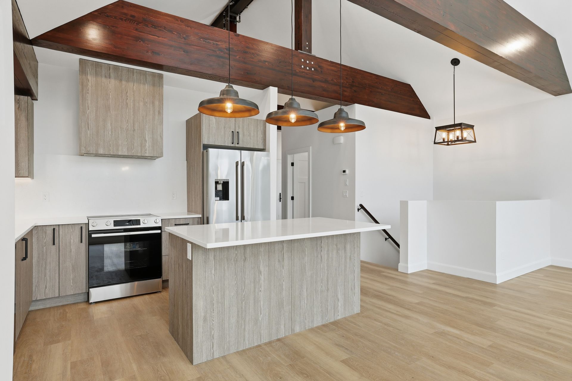 Modern kitchen with white island, wood beams, stainless appliances, and pendant lights