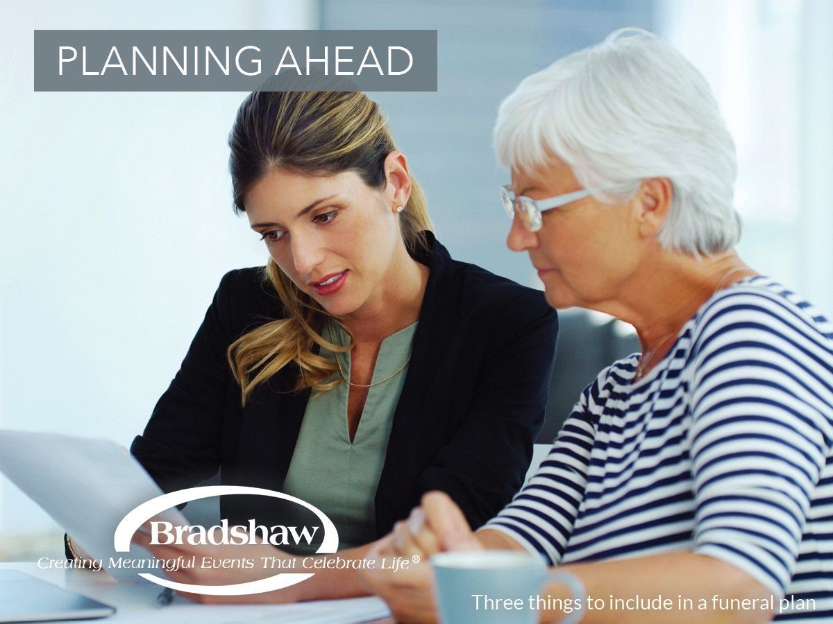 Woman reviewing papers with another woman, discussing funeral planning.