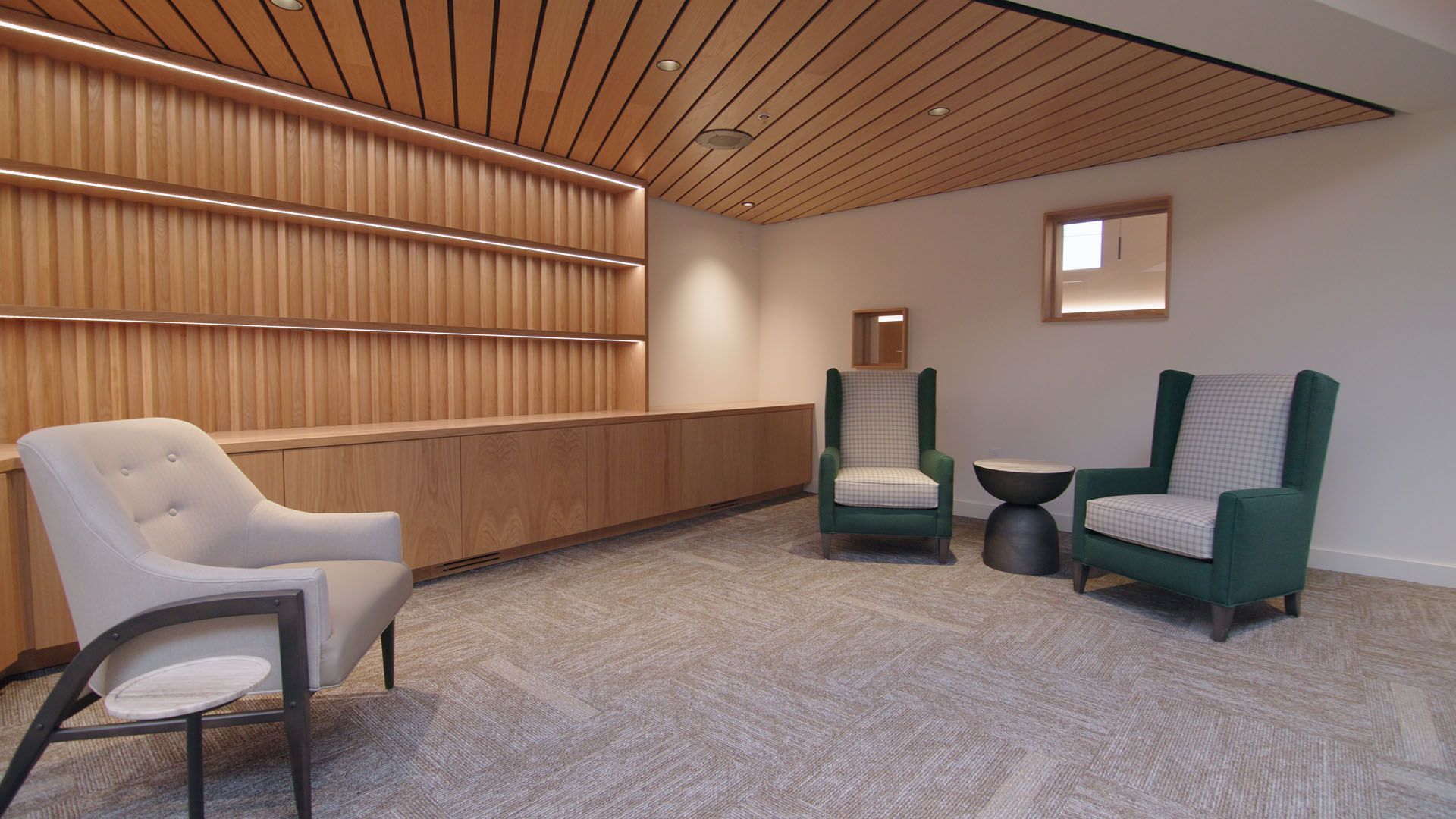 Reception area with wooden paneling, three armchairs, and a small table.