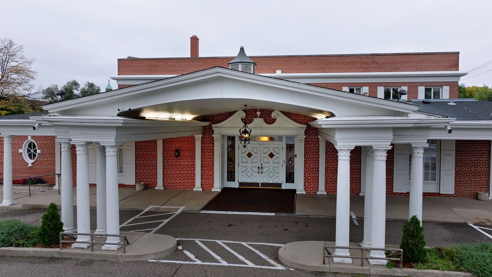 A large white building with a brown roof and a lot of windows.