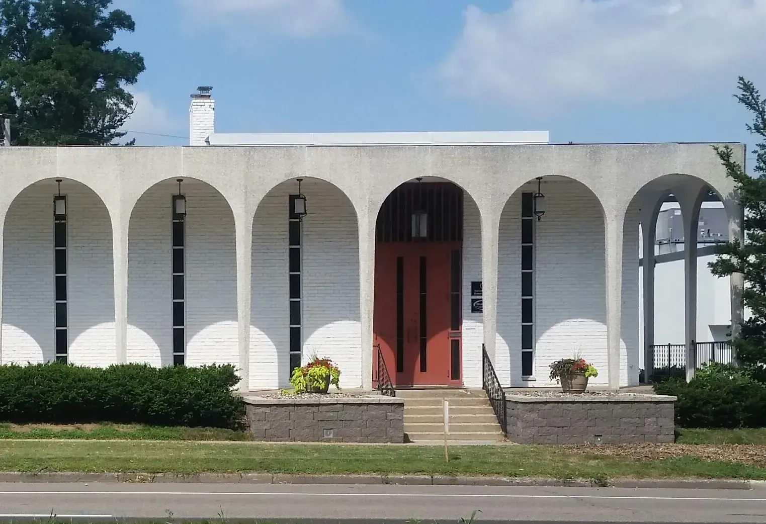 A large white building with a brown roof and a lot of windows.