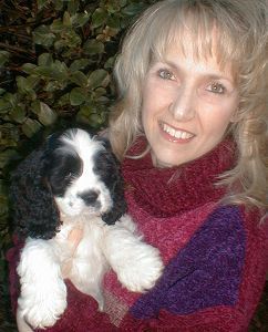 A woman is holding a black and white puppy in her arms.