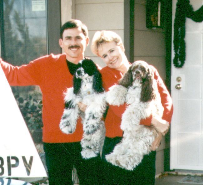 A man and woman holding two dogs in front of a sign that says bpy