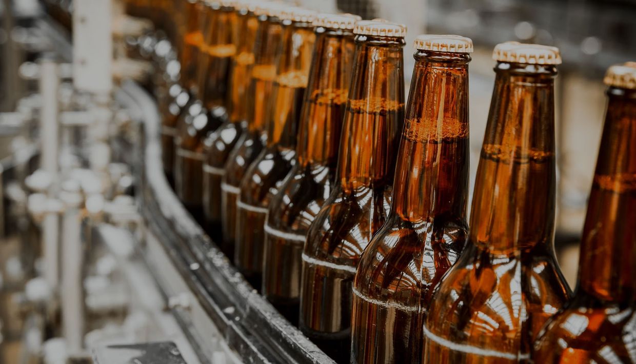 A conveyor belt filled with bottles of beer in a brewery.