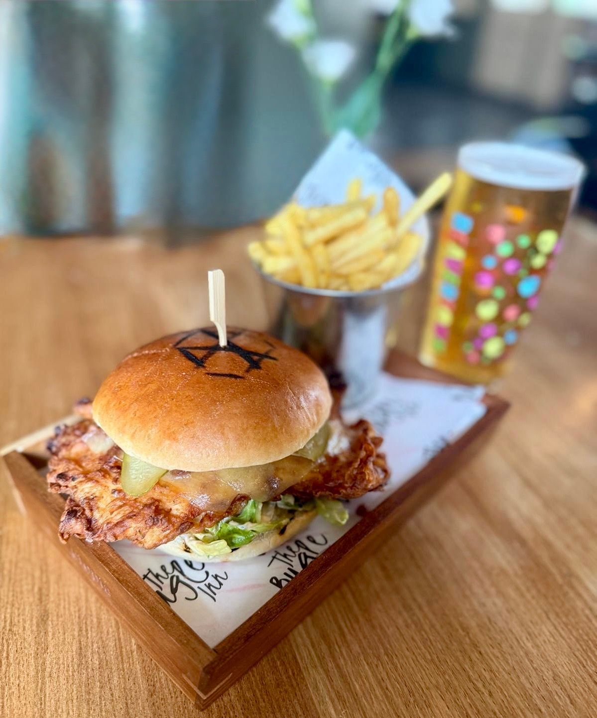 Burger slider with fries and a drink on a wooden tray in a restaurant setting