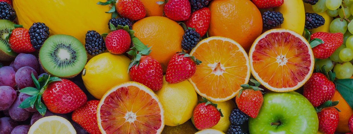 A variety of fruits and berries are sitting on top of each other on a table.