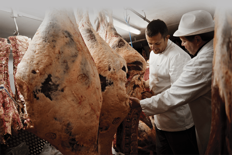 Two men are looking at a large piece of meat