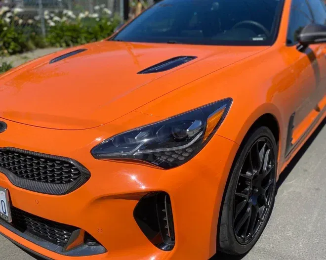 a bright orange car is parked on the side of the road