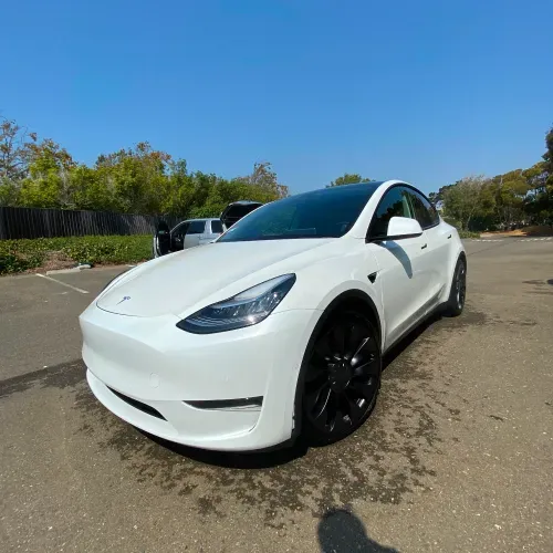 a white tesla model y is parked in a parking lot .