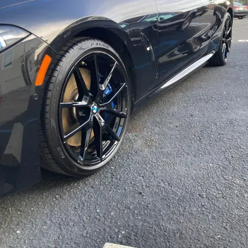a black bmw is parked on the side of the road .