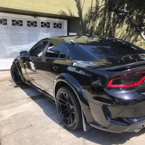 a black dodge charger is parked in front of a garage door
