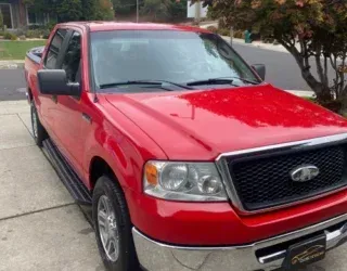 a red ford truck is parked on the side of the road .