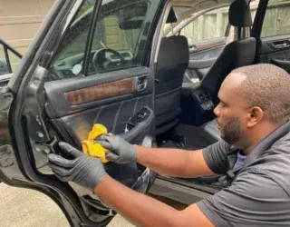 a man is cleaning the inside of a car with a cloth .