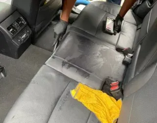 a person is cleaning the back seat of a car with a vacuum cleaner .