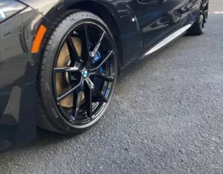 a black bmw is parked on the side of the road .