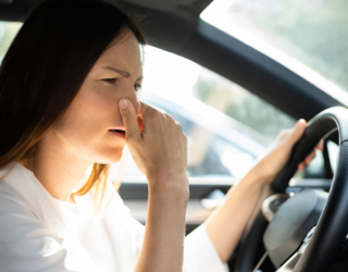 a woman is holding her nose while driving a car .