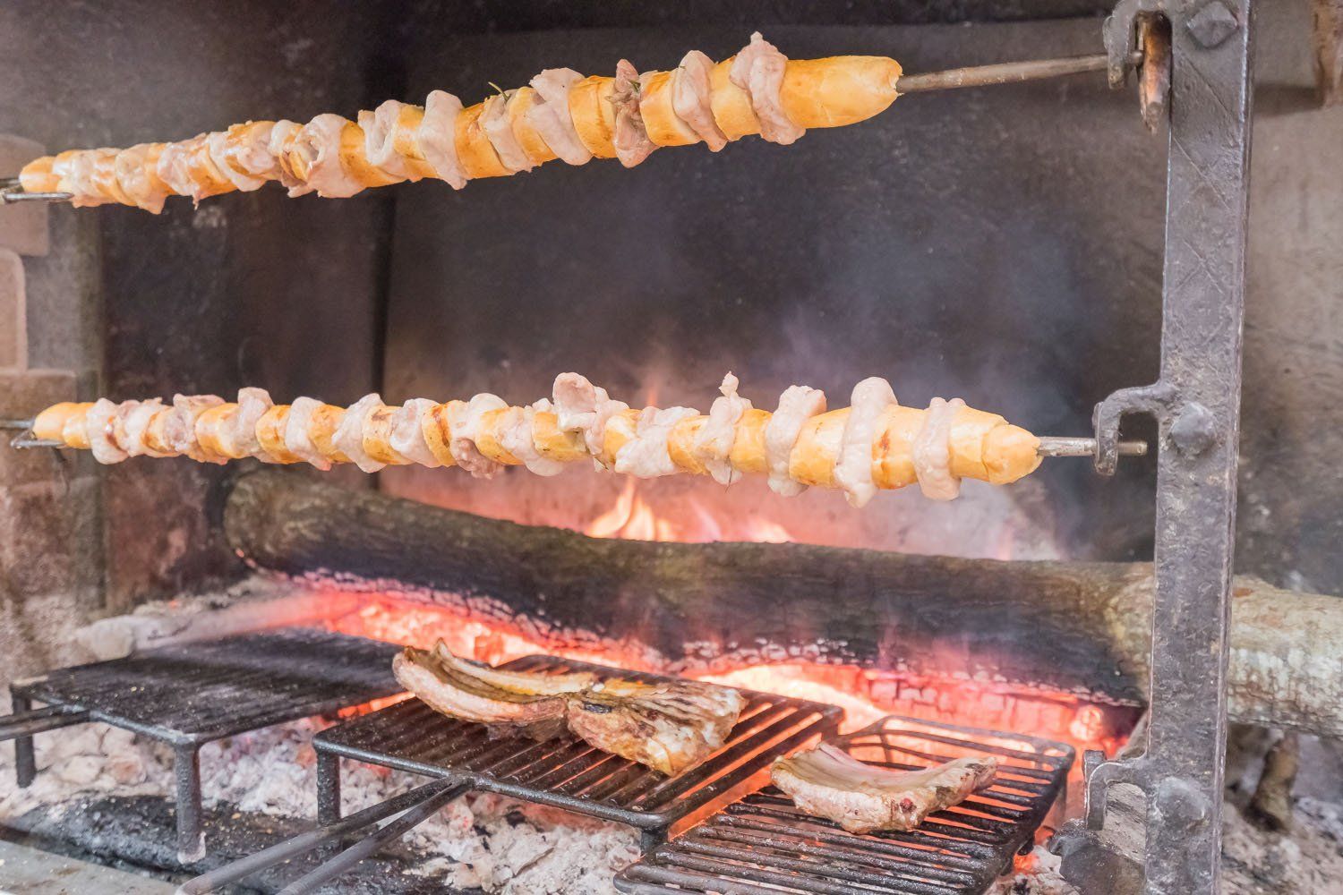 Spiedini di carne grigliata che cuociono su fiamme libere in un barbecue fumoso