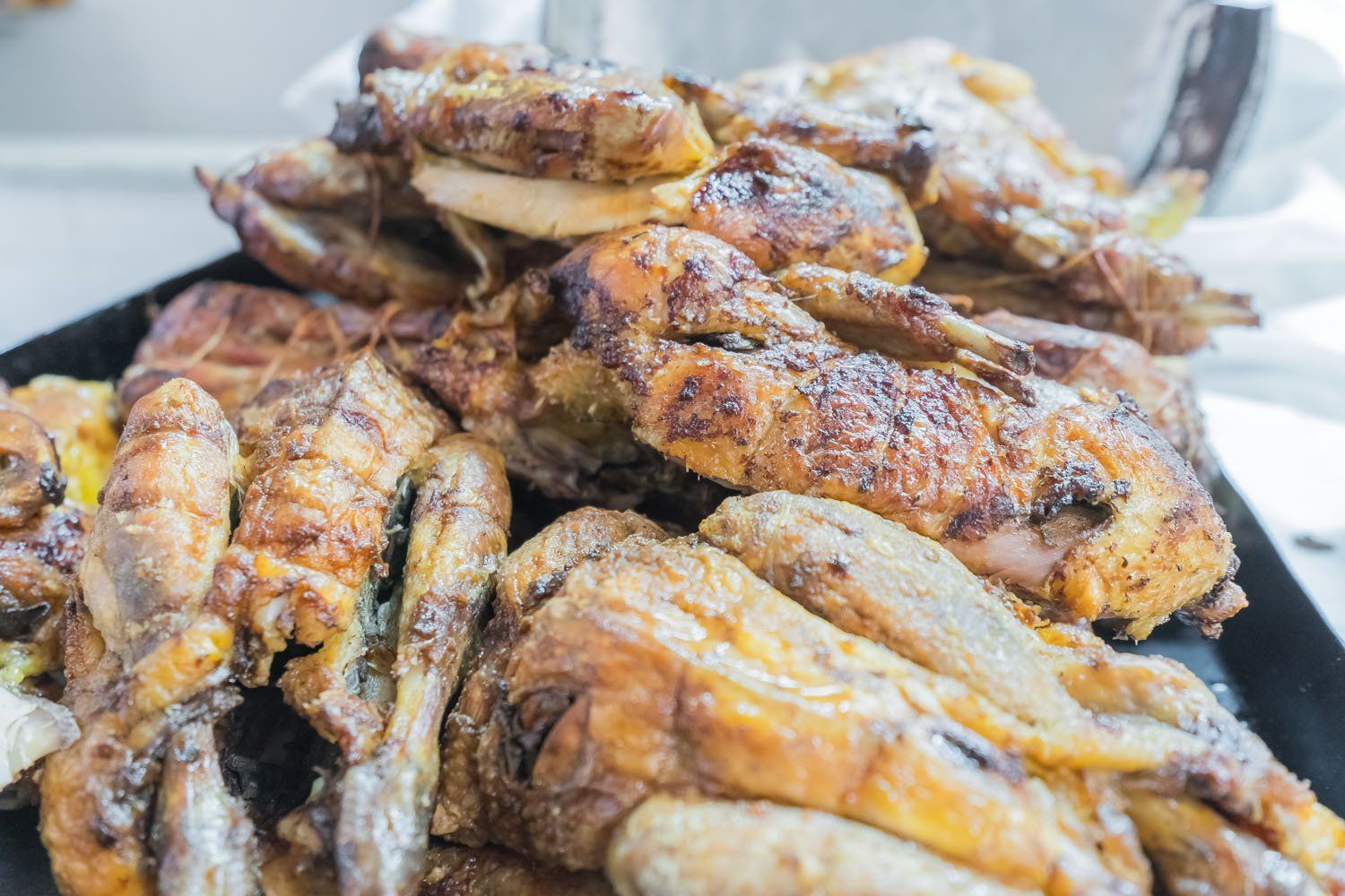 Pezzi di pollo grigliati, dorati e conditi, disposti su un vassoio, con il fumo visibile.