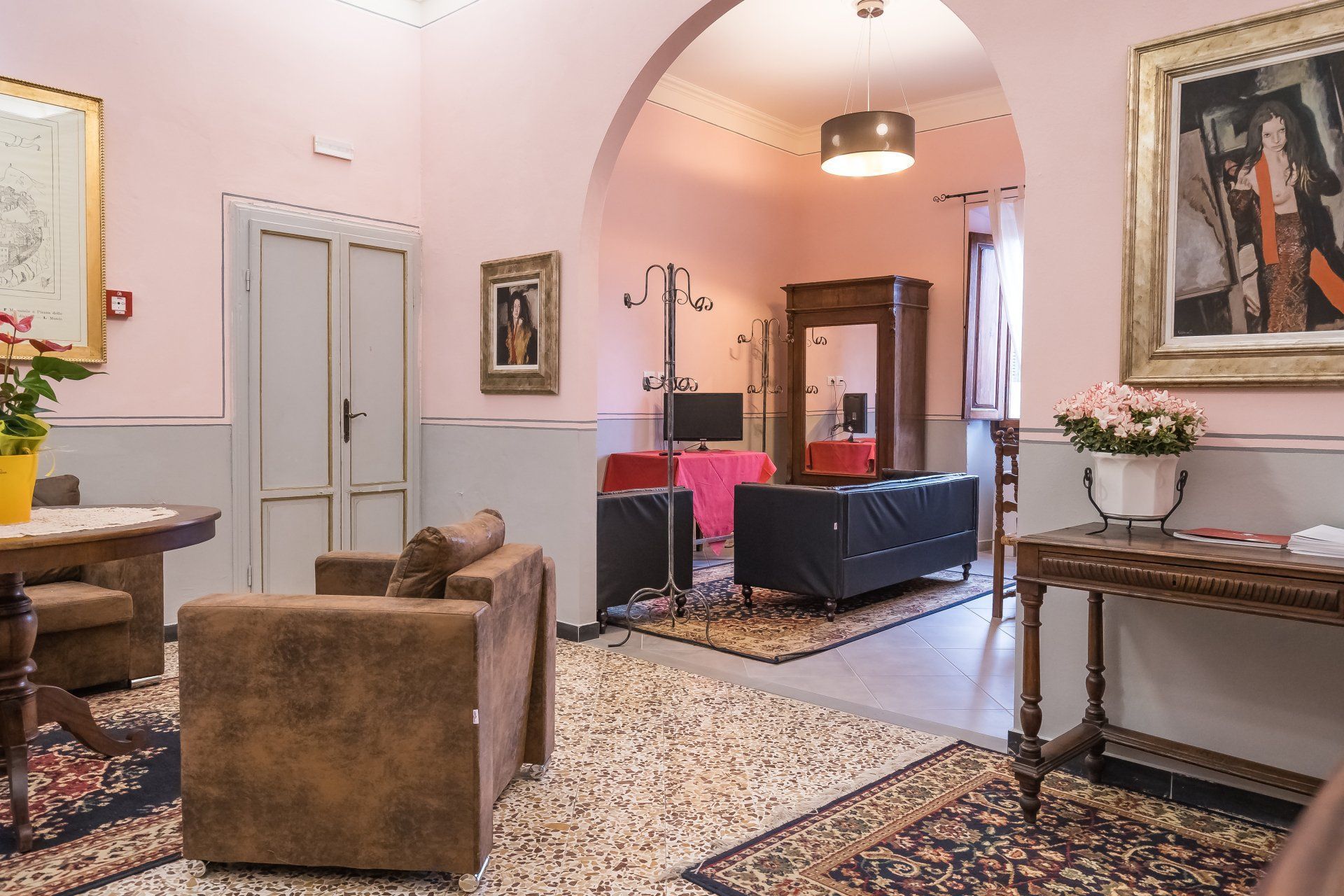Elegante soggiorno rosa con porta ad arco, divani, tappeto a motivi geometrici e opere d'arte incorniciate.