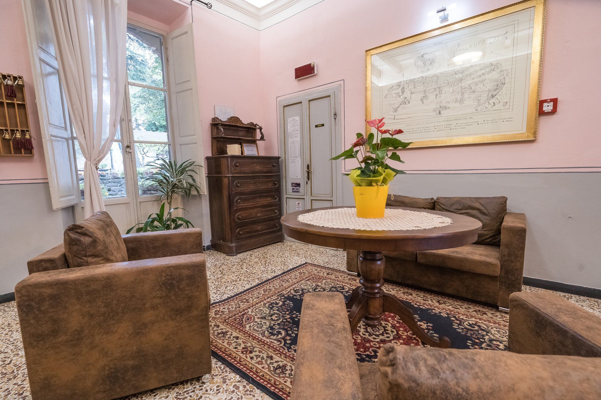 Elegante salotto con tappeto decorato, tavolo rotondo, poltrone, finestra, armadio e mappa a parete.
