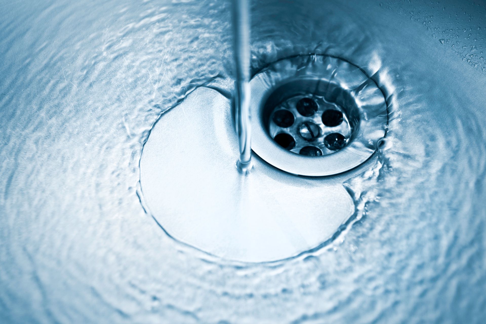 A drain with water running from the kitchen faucet, showcasing Drain Cleaning Hesperia CA by Roto-Rooter Plumbers and Septic Service A drain with water running from the kitchen faucet, showcasing Drain Cleaning Hesperia CA by Roto-Rooter Plumbers and Septic Service