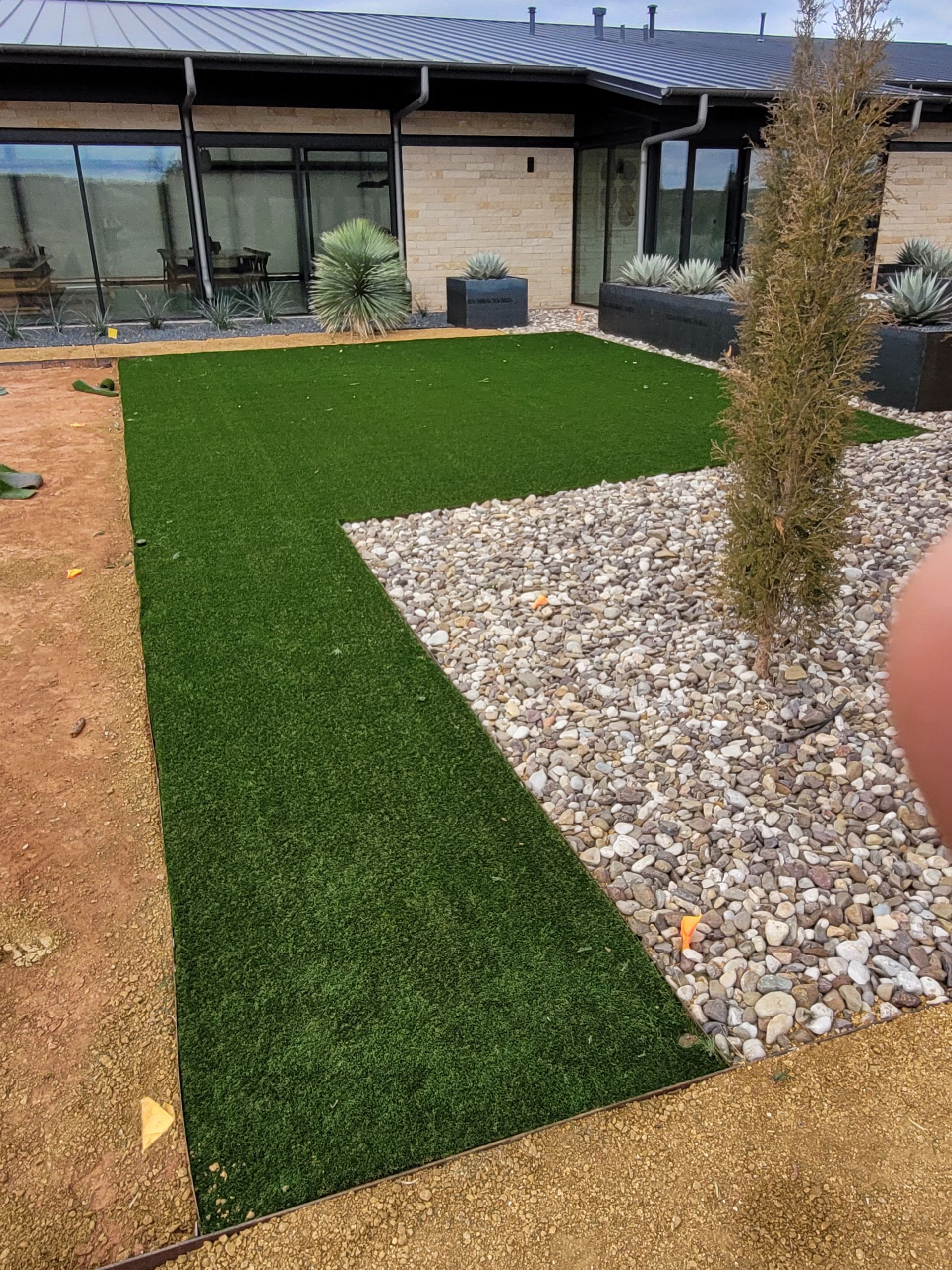 Landscaped courtyard with artificial grass, white gravel, and a row of modern windows.