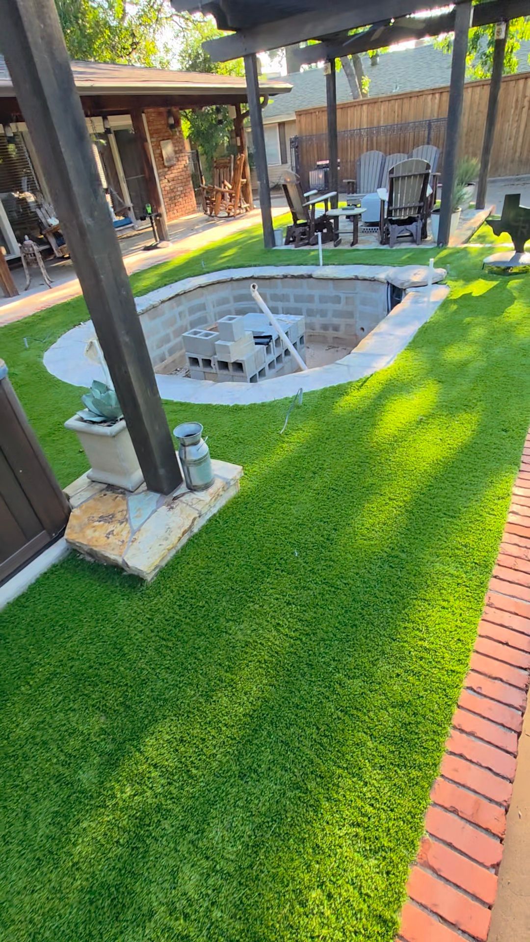Backyard patio with a small sunken pool, bright green turf, and covered seating area
