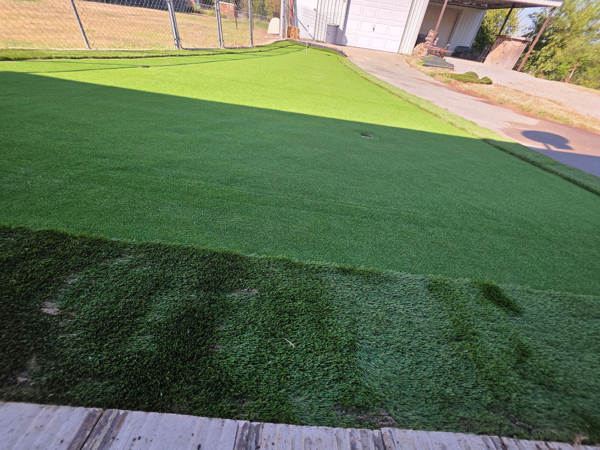 Sunlit lawn with a dark shadow across the grass in a suburban yard
