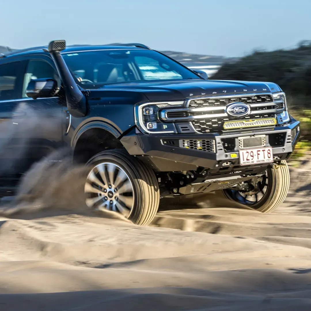 Black Ford pickup truck driving through sand, kicking up a dust cloud. — TJM Albury Pty Ltd in South Albury, NSW